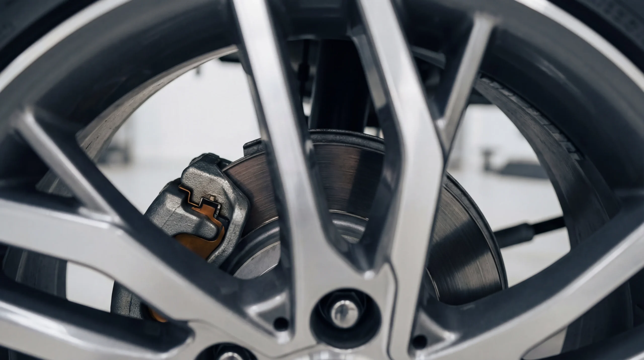 How to check brake pads shown through wheel well with caliper rotor and pad edge visible in sharp detail
