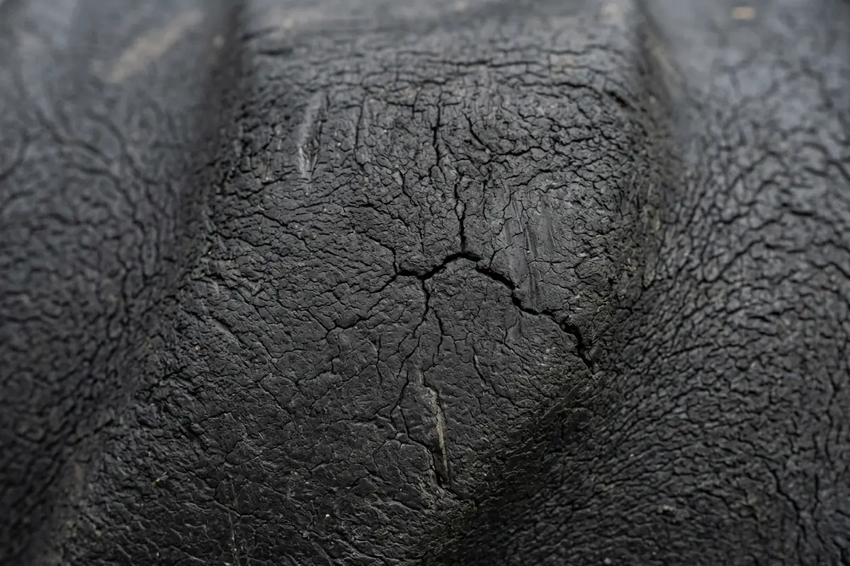 Close-up of a damaged tire sidewall with a rounded bulge and fine cracks in the rubber, a replace-not-repair failure